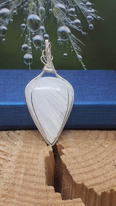 pendentif scolécite goutte inversée et fil argenté devant boite cadeau bleue