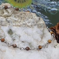 bracelet fin oeil de tigre 4 mm facetté et acier inoxydable sur la pierre devant le bourgeon