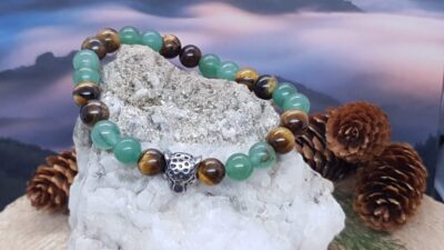 bracelet aventurine verte et oeil de tigre posé sur la pierre et devant le ciel nuageux rosé