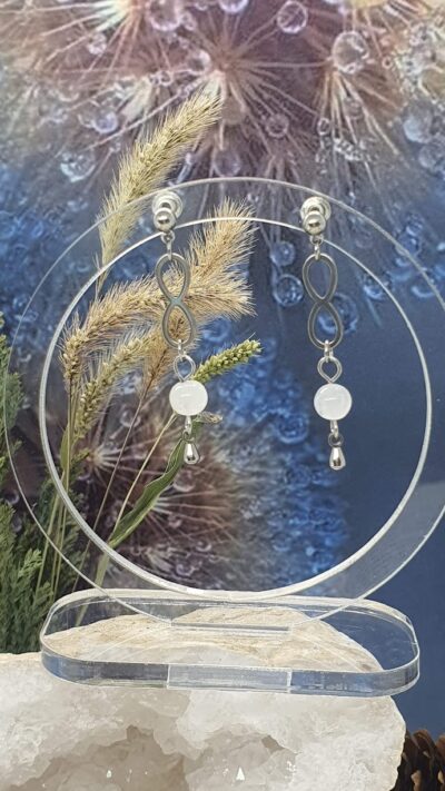 Les boucles d'oreilles en péristérite et symbole infini sur leur portoir en plexiglas