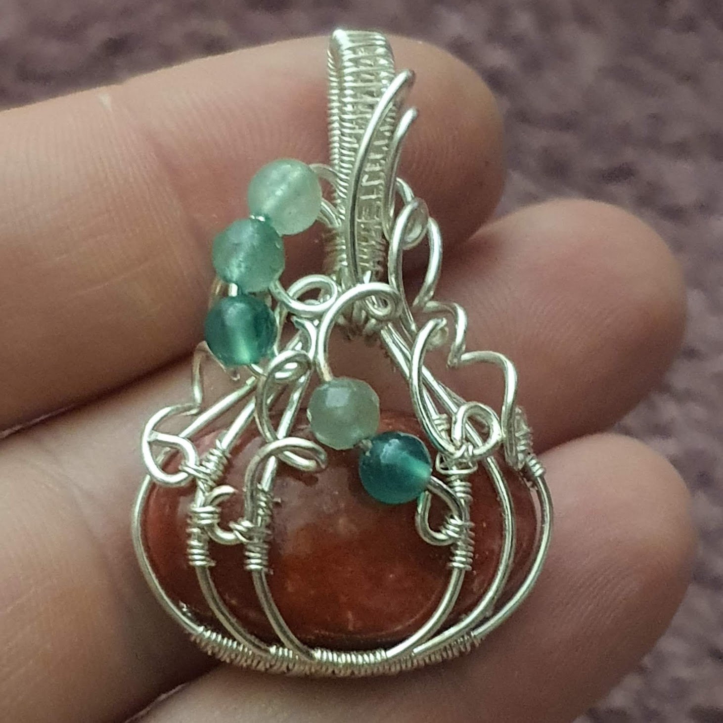 pendentif thulite rose en forme de citrouille dans la main