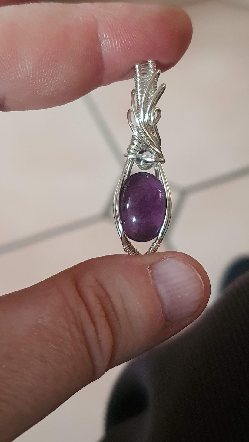 pendentif améthyste et cristal de roche entre 2 doigts