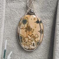 pendentif en jaspe orbiculaire posé dans son plateau gris