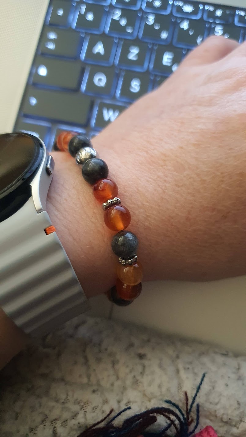 bracelet cornaline et larvikite orange et noir porté sur ordinateur